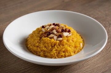 A bowl of yellow rice pilaf topped with almonds and berries