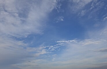 A serene view of a bright blue sky with soft white clouds scattered across, creating a peaceful and natural atmosphere. Perfect background for concepts of freedom, tranquility, weather