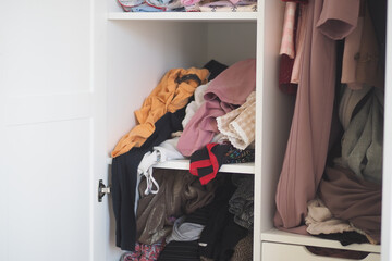 Clothing storage cabinet filled with assorted garments