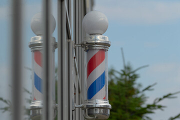 A vibrant barber pole featuring red and blue stripes stands out against a clear sky, symbolizing classic barber shop traditions.