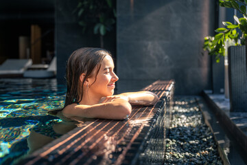 Girl at the pool edge in warm daylight. Calm wellness moment.