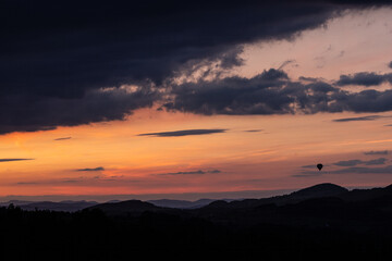 the silhouette of a hot air balloon in a scenic landscape at sunset
