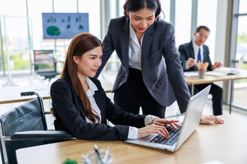 Confident asian woman in wheelchair collaborates with her business team in office setting, representing workplace equality, leadership diversity, and inclusive teamwork for professional growth