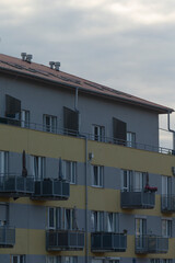 A contemporary residential building featuring balconies and a muted color scheme against a cloudy sky, ideal for urban lifestyle concepts.