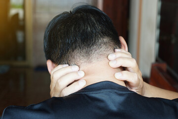 A man holding his neck with both hands, showing discomfort or pain. Concept of neck pain, stress, fatigue, or muscle tension, often related to office work, poor posture, or daily strain.