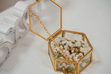 Elegant Hexagonal Glass Ring Box with Gold Accents. Wedding Bands Surrounded by White Baby's Breath Flowers, Luxury Ceremony Decor