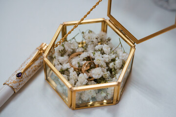 Elegant Hexagonal Glass Ring Box with White Baby's Breath, Gold Accents and Wedding Bands on White Background, Romantic Ceremony Style