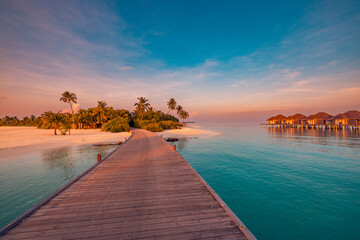 Obraz premium Stunning Maldives sunset beach landscape with luxury resort, summer vacation, scenic pier and jetty leading into tropical colorful nature paradise, lush green palm trees over calm sea horizon travel