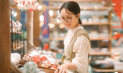 Asian woman shopping on Christmas and Happy new year holidays choosing present in gift shop indoors market