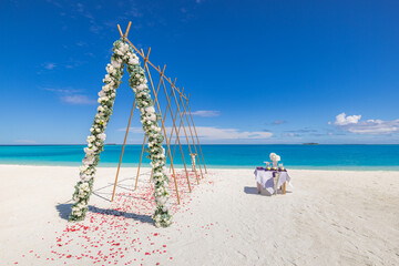 Romantic beach wedding with floral arch and petals decoration by the sea, luxury tropical...