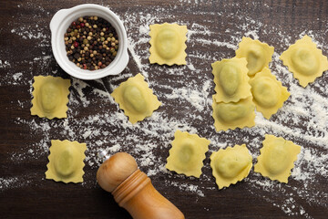 Fresh stuffed ravioli big size on wooden table with flour and eggs