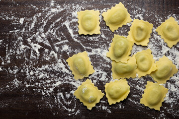 Flat lay composition with raw ravioli on wooden table. Italian pasta