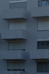 A close-up view of a modern residential building facade showcasing multiple balconies with shutters and large windows. Ideal for real estate and architectural themes.