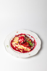 Close-up of a slice of strawberry pie served with a scoop of ice cream on a white background