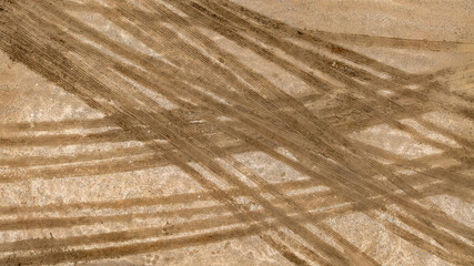 Aerial top view tire track on dirt sand mud, Texture of wet mud road with puddle and Tyre or tire track in countryside, Wheel tyre or tire track on mud, texture and background.