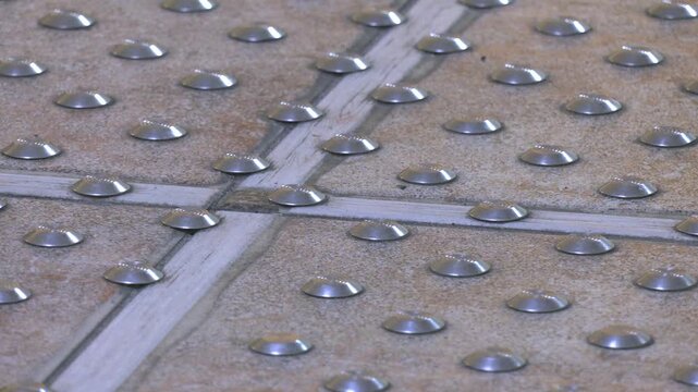 Warning, hazard tactile indicator closeup. Stainless steel tactile ground surface indicator, truncated cone installed on the ground or floor surface to provide cues for blind or vision-impaired people