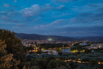 Florence, Italy at night with illuminated cathedral, Arno River reflections, and historic city skyline.