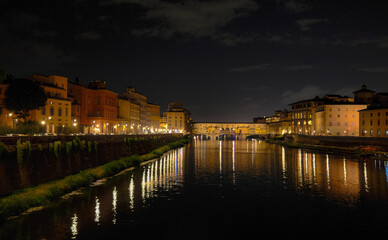 Florence, Italy at night with illuminated cathedral, Arno River reflections, and historic city skyline.