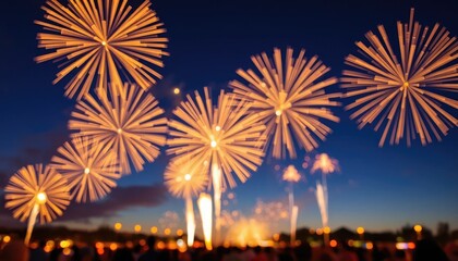 Golden fireworks bloom in the twilight sky over a silhouetted crowd