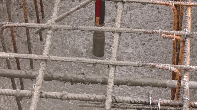 Iron Grate or Reinforcement on the Ground Poured With Concrete at a Construction Site. concrete casting work. using concrete vibrator for compacting concrete of stiff consistency
