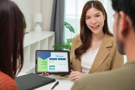 asian financial advisor presenting charts and data on a tablet during couple client meeting.financial planning and decision-making