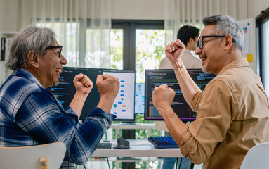 Senior developer team celebrates success in software collaboration and coding at a modern computer workstation