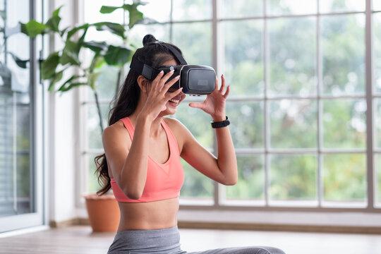 Asian woman wear virtual reality glasses choosing training yoga class online at home