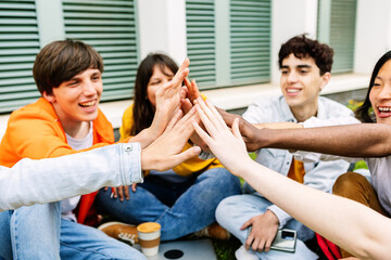 Diverse student people stacking hands together sitting outdoors at college campus. Youth community concept with young group of millennial students joining hands together showing unity and oneness.