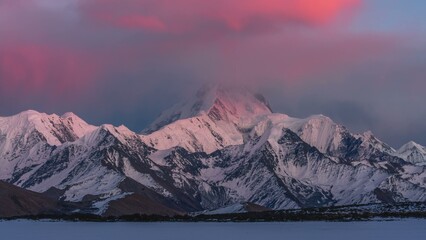 Snow capped mountains at sunset with a pink glow