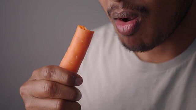 Eating fresh carrot in close-up shot at indoor setting