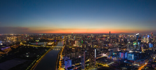 Wuhan China city skyline lights up at dusk across the river with many buildings showing bright illumination 