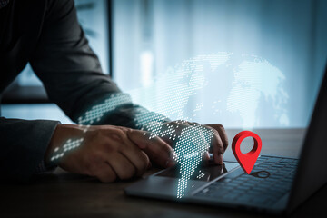 Businessman using laptop with digital world map and red location pin symbol, representing global network, GPS navigation, worldwide connection, and modern technology in business.