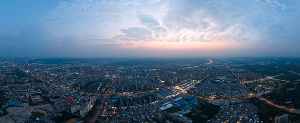 The vast city of Suizhou, China spreads out under a soft twilight sky with lights twinkling from buildings and roads.