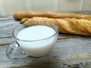 tasty pieces of baguette lie on a wooden table next to a cup of milk