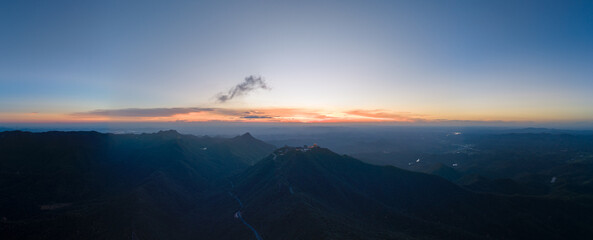 Sunrise illuminates mountains and distant horizon over Suizhou, China, painting the sky with soft...
