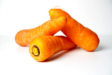 Close-up Shot of Three Fresh Organic Carrots on White Background: Vibrant Orange Vegetables Ready for Cooking or Juicing