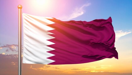 Qatar national flag waving in the wind with a bright sky and clouds in the background.