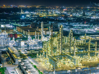 Large petrochemical plant brightly illuminated at night, located on the industrial outskirts of a...