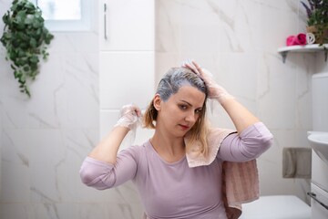 Woman dyeing her hair at home in the bathroom
