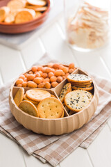 Various salty snacks in a round bowl on white table.