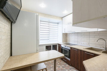 kitchen with white cabinets, wood-grain lower cabinets, and a built-in dining table. Features a window with blinds and tiled backsplash