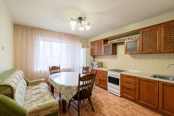 cozy kitchen-dining area with wooden cabinets, a floral sofa, and a round table by a window