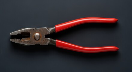 Fototapeta premium Tool of Precision: A detailed shot of a set of pliers, its red handles offering a striking contrast against a dark backdrop, the tools are symbolic of precision.