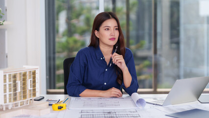 Asian adult female architect designing building plans modern architecture project creative workplace office studio interior