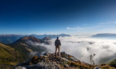 Mac standing on a mountain peak, high above the clouds. Symbolic of achieving objectives and battling adversity.