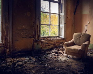 Old armchair by the window in an old, abandoned, empty house.