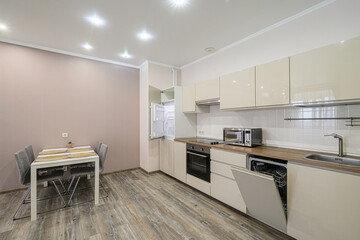 Bright kitchen with modern appliances, dining table, and stylish decor. The design features glossy cabinets and wood-look flooring