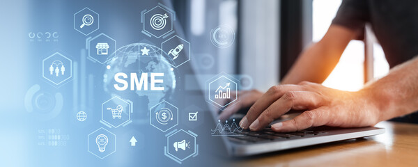 Businessman typing with SME icons overlay on digital interface background.