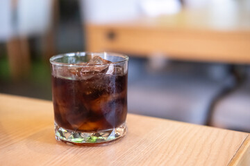 A glass of Cola on the table with bokeh background