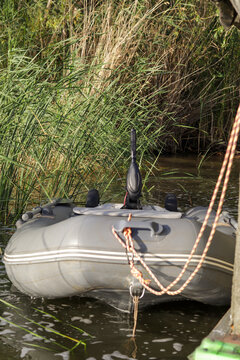 Green rubber boat with fishing nets on the river. Rubber boat on coast of lake. Fish-finding fathometer on rubber boat, Inflatable boat at the river berth. 